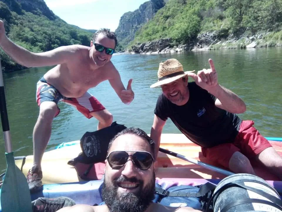 Trois hommes en canoë souriant dans les gorges de l'Ardèche